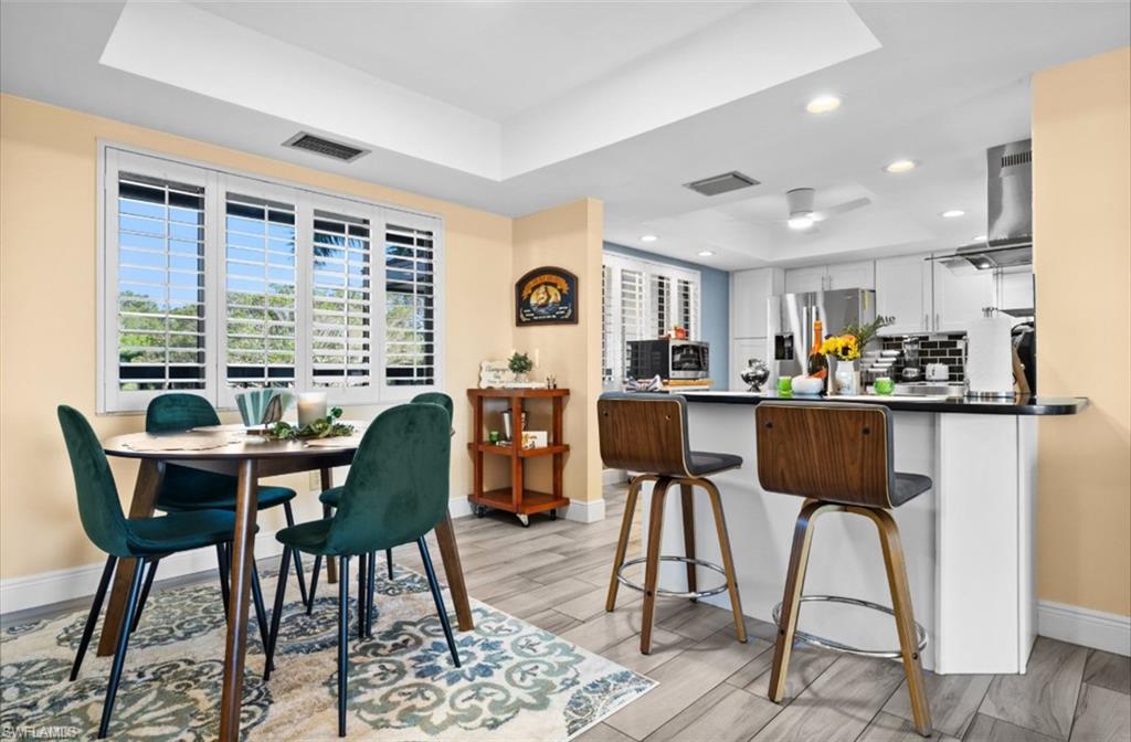 Recessed lighting, tray ceiling, plantation shutters, wood-finish flooring, and a kitchen peninsula with a countertop