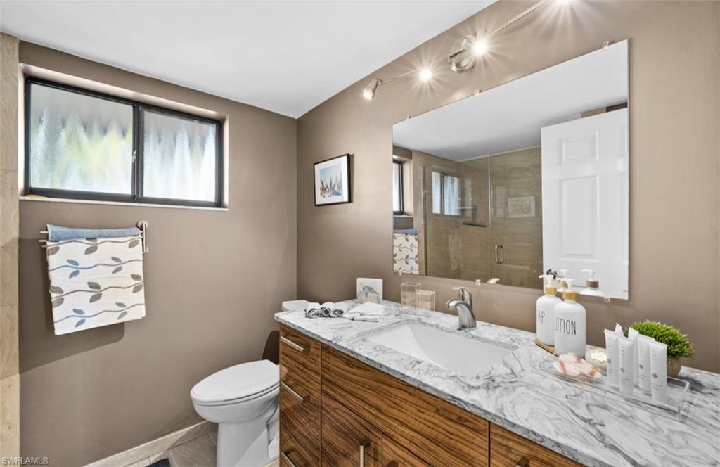 Floating wood-finish vanity with an integrated rectangular sink and stone countertop