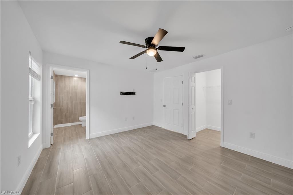 Spacious room featuring wood-finish tile flooring, a ceiling fan with integrated lighting, and a window with blinds