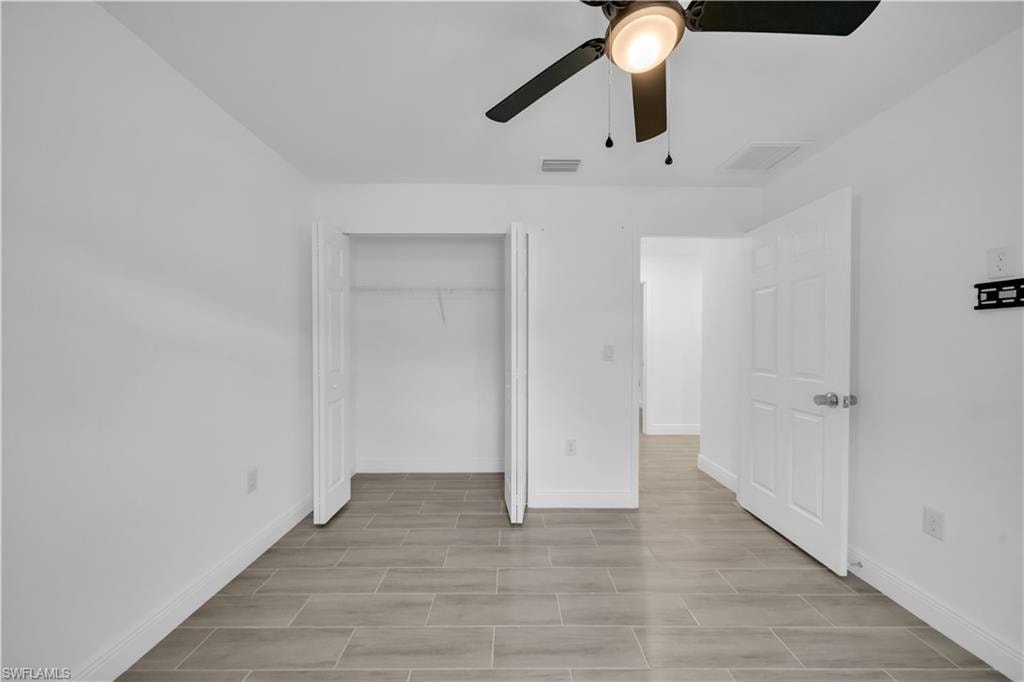 Tile flooring throughout, clean white walls, a ceiling fan with integrated lighting, and a bi-fold closet