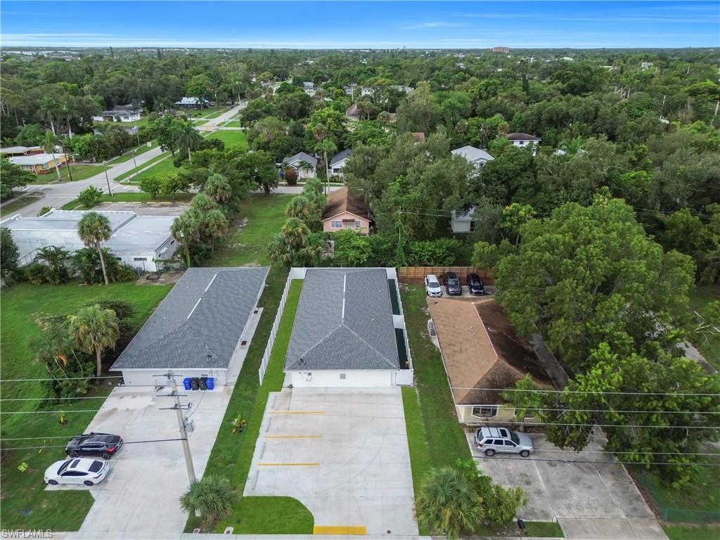 Two structures featuring gray shingle roofs, white exteriors, and concrete parking areas