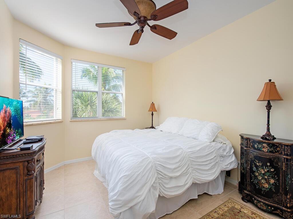 master tiled bedroom with ceiling fan and multiple windows