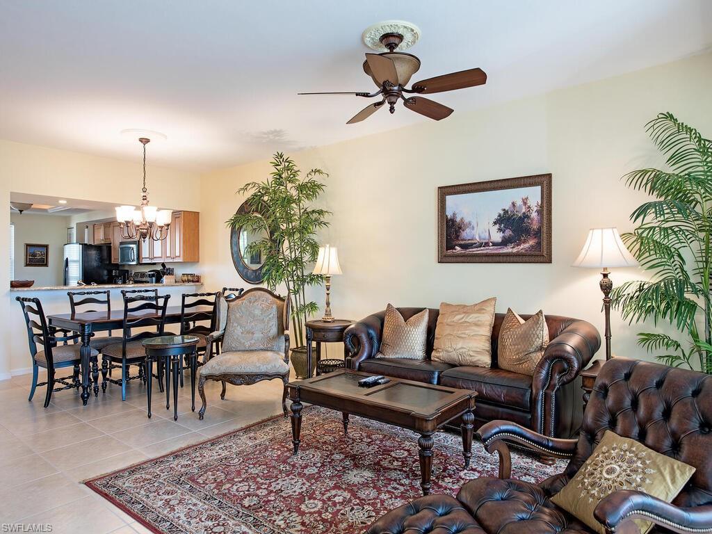 Tiled living room with ceiling fan with notable chandelier