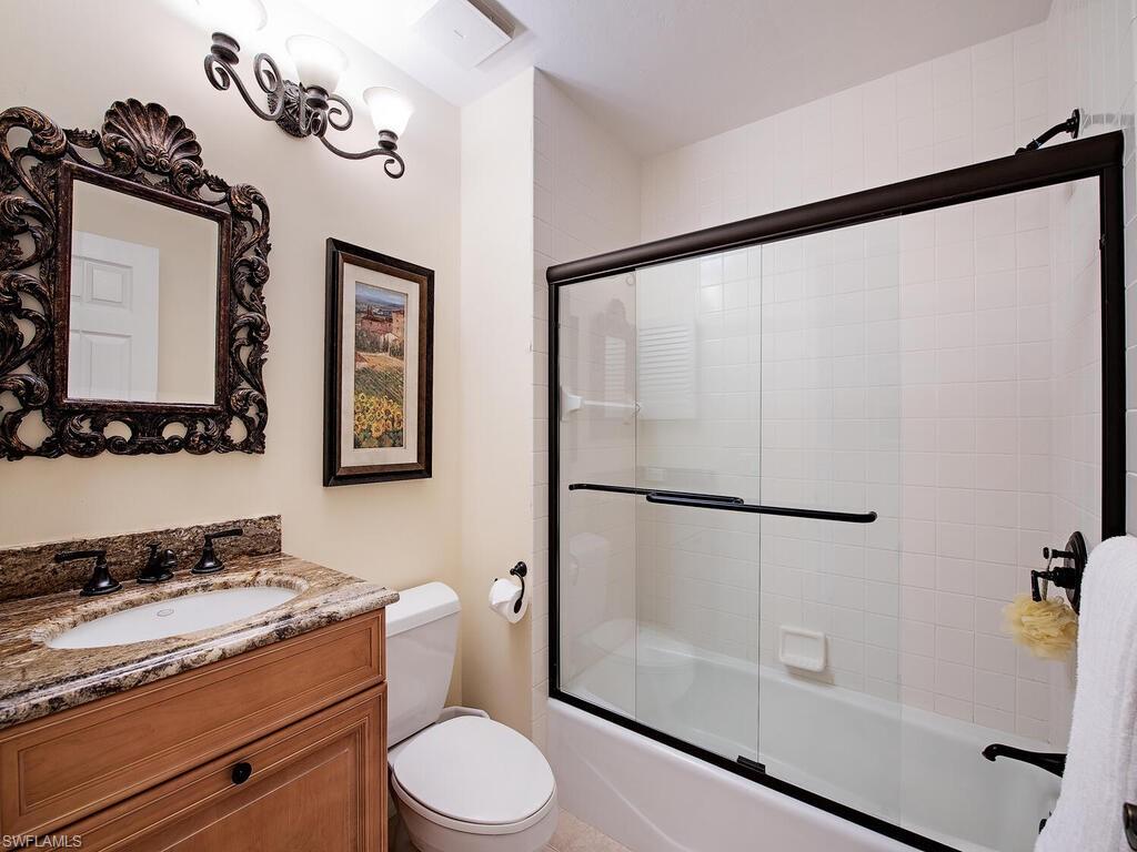 Full guest bathroom featuring vanity, toilet, and combined bath / shower with glass door
