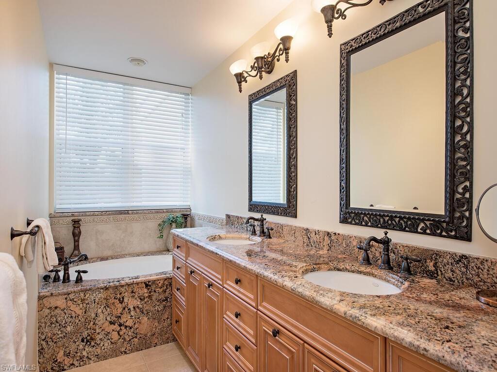 Master bathroom with vanity, a healthy amount of sunlight, tile patterned floors, and tiled bath