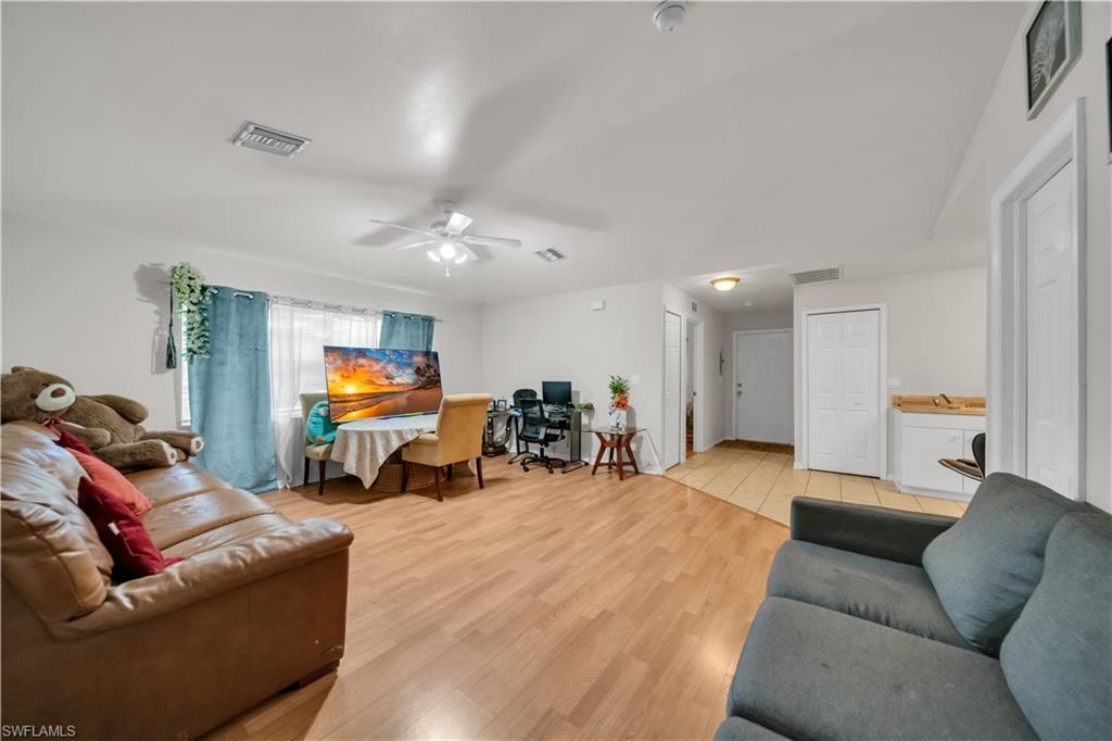 Spacious room featuring wood-finish flooring, light-toned walls, a ceiling fan, and a built-in cabinet