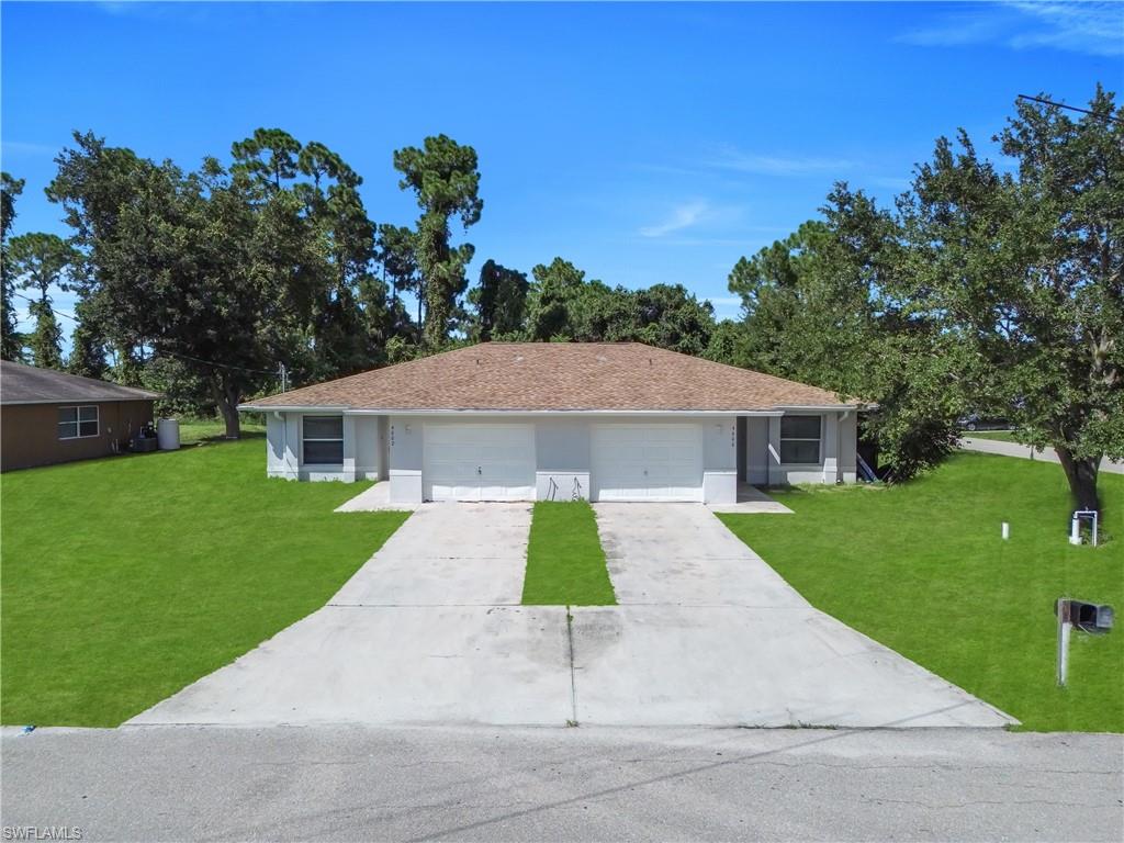 Duplex property featuring a brown shingle roof, two white garage doors, and two concrete driveways