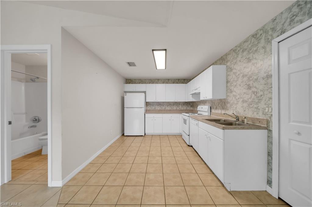 Kitchen with white cabinetry, a double basin sink, and tile flooring