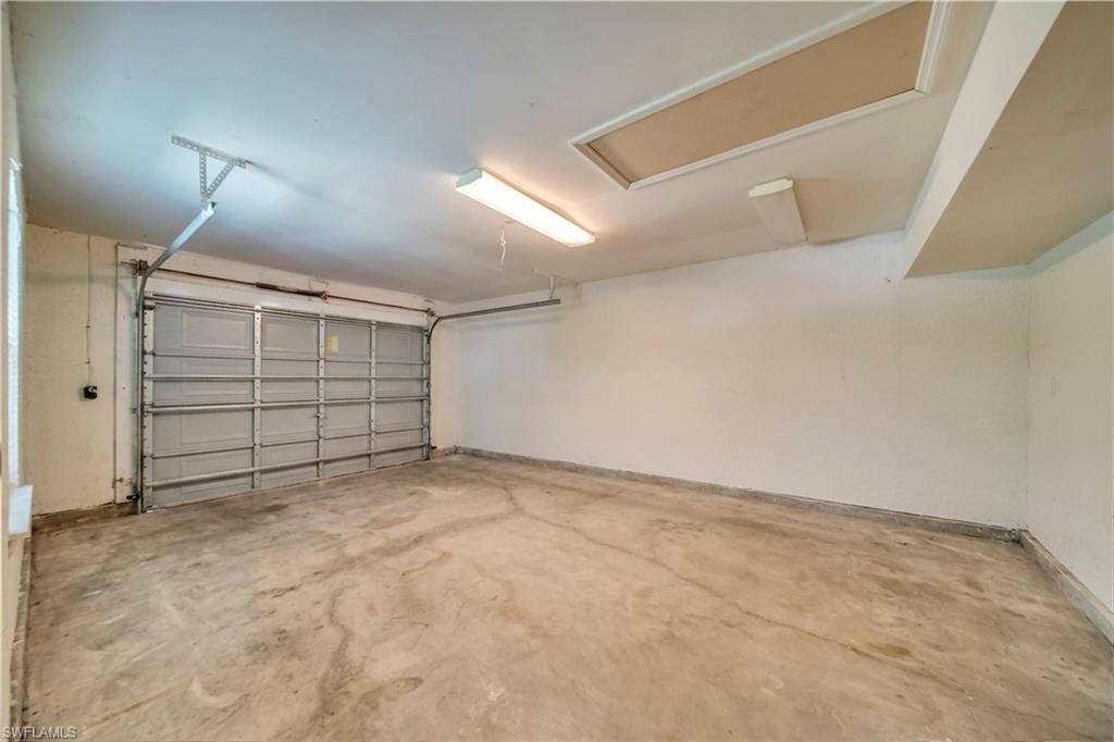 Spacious garage with an overhead door, concrete flooring, and ceiling-mounted lighting