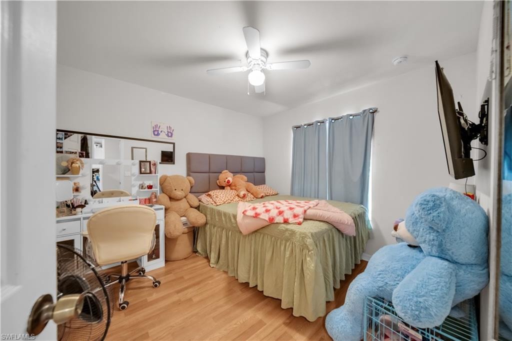 Wood-finish flooring, ceiling fan, and window with light-filtering curtains