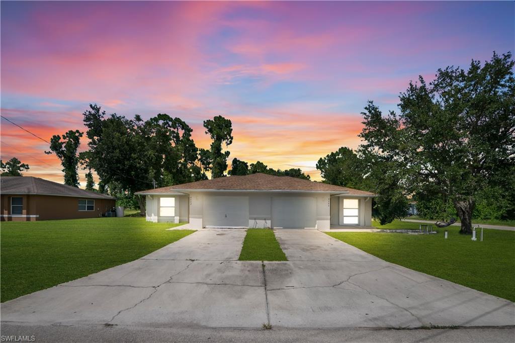 Duplex residence featuring two distinct driveways, individual garages, and a light-toned exterior finish