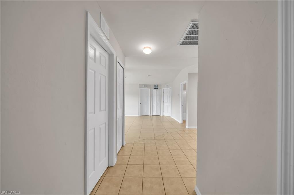 Light-colored tile flooring, overhead lighting, white paneled doors, and light wall finishes