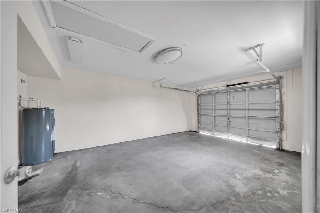 Interior garage featuring a water heater, concrete flooring, and ceiling-mounted lighting