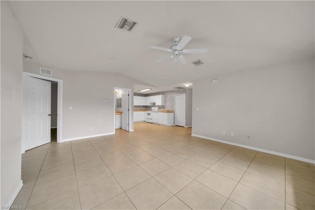 Expansive tiled flooring throughout, vaulted ceiling, and a ceiling fan with light fixture