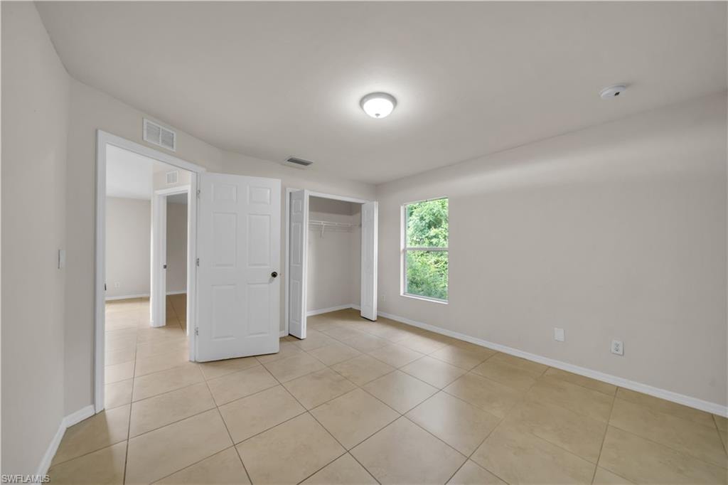 Neutral wall paint, ceiling-mounted light fixture, tile flooring, and built-in closet