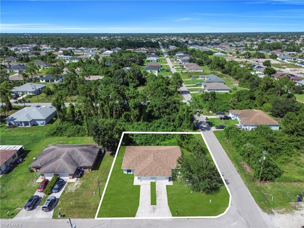 Expansive aerial view showcasing a newly constructed residence situated on an oversized corner lot with mature tree-lined landscaping