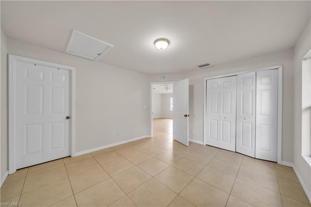 Neutral wall paint, tile flooring, flush mount ceiling light, and built-in bifold closet doors