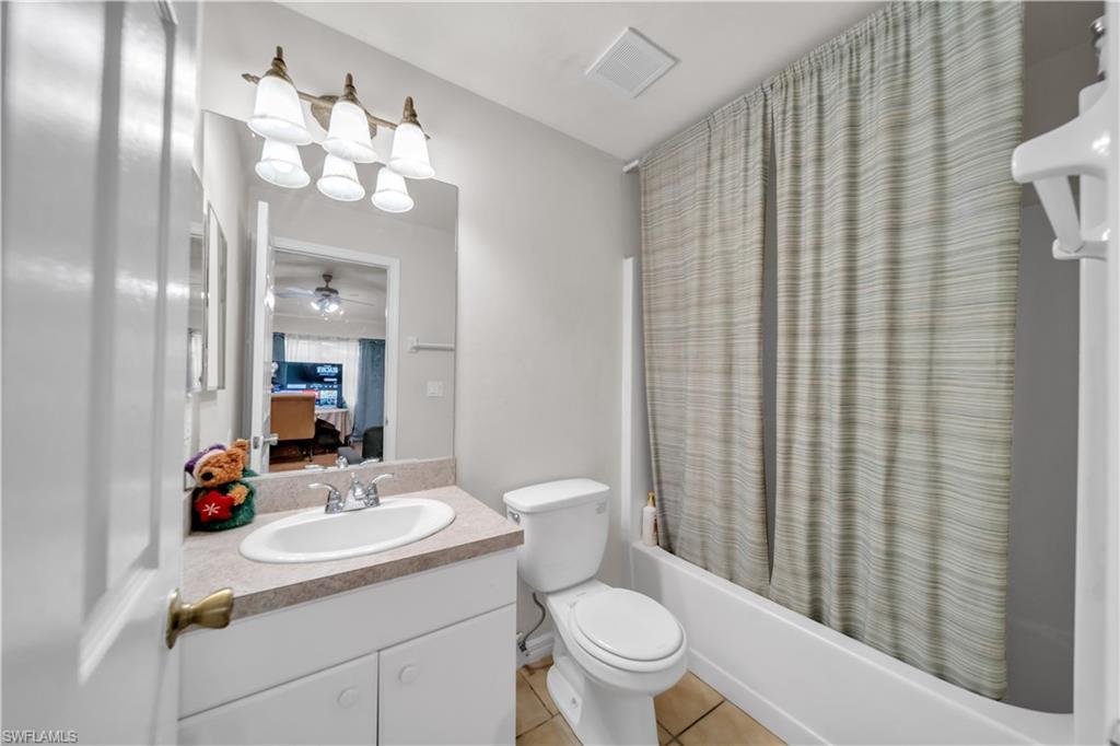 Contemporary bathroom featuring a round vessel sink with wood-finish vanity, polished chrome fixtures, and abundant mirror lighting