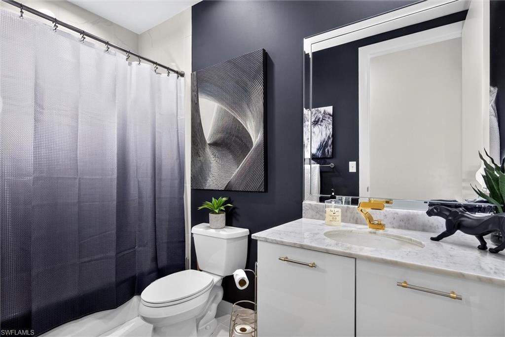 Vanity with a white countertop and integrated sink, gold-finish faucet, and white cabinetry with gold-finish pulls