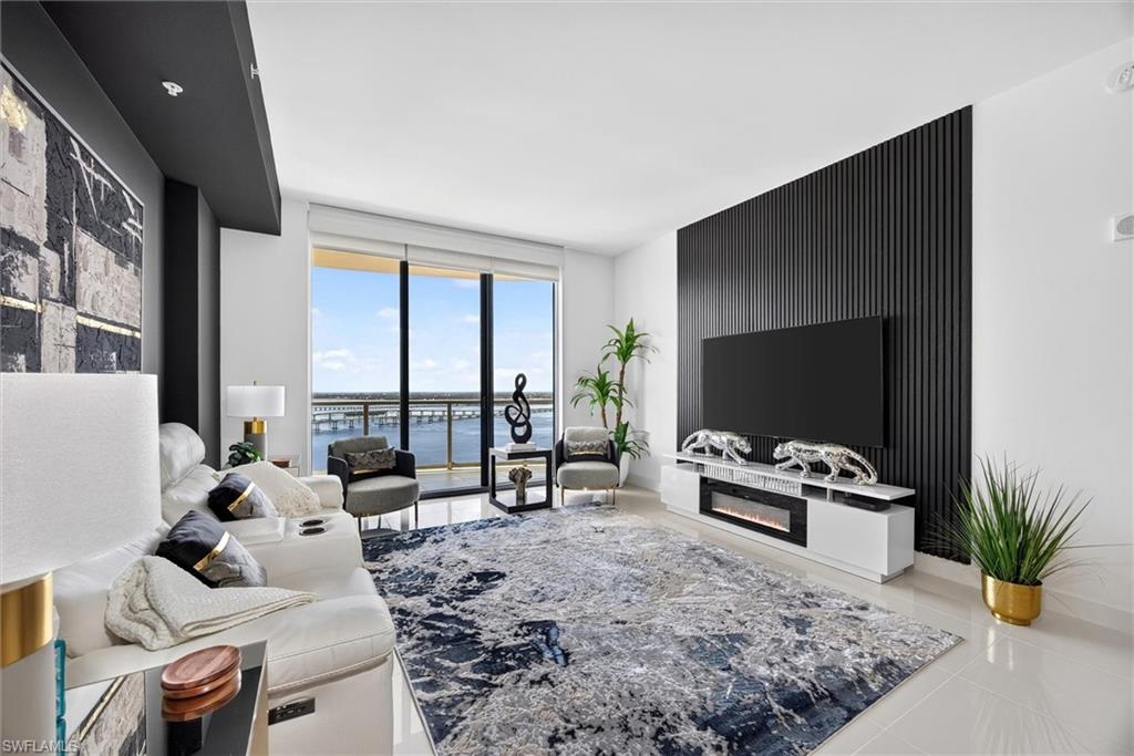 Floor-to-ceiling windows, sleek black accent wall paneling, built-in entertainment console with electric fireplace, recessed lighting, and large format tile flooring