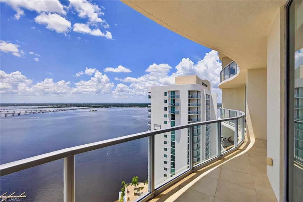 Curved balcony with glass railing, tile flooring, and water scenery