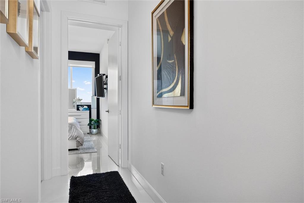 Bright hallway featuring clean white walls, white trim molding, and a black entry runner