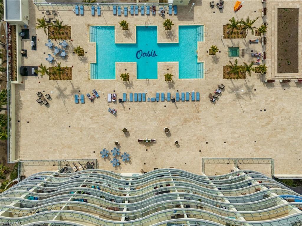 Expansive amenity deck featuring a large multi-section pool, an outdoor spa, and multiple landscaped planters