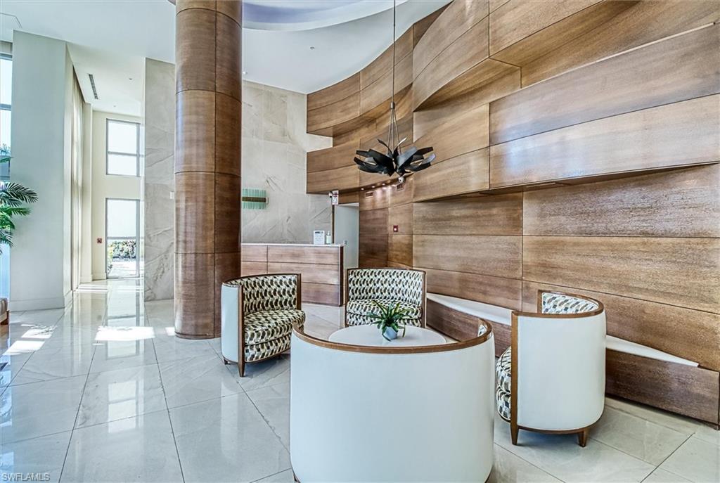 Polished tile flooring, a curvilinear wood-paneled feature wall, a wood-clad structural column, and a modern chandelier