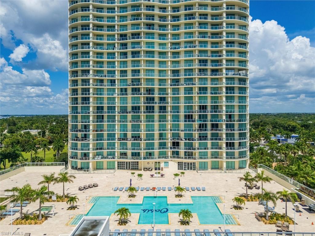 Oceanfront high-rise residence featuring resort-style amenities including zero-entry heated pool with cabana seating, lush tropical landscaping with mature palms, and expansive sundeck with lounge areas