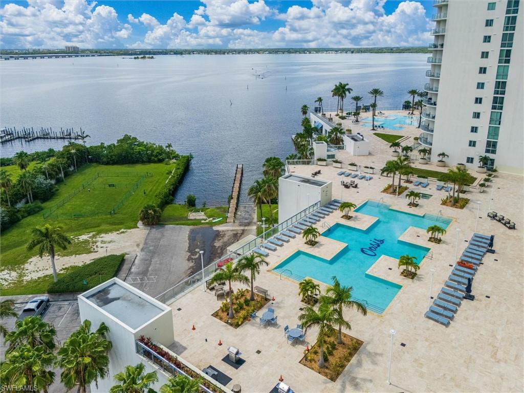 Expansive waterfront setting featuring a multi-level pool deck, a large swimming pool with integrated tanning ledges, and a separate aquatic area