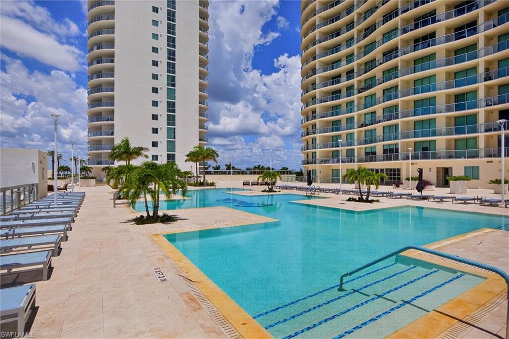 Expansive outdoor amenity deck featuring multiple swimming pools, tropical landscaping, and two high-rise buildings with private balconies