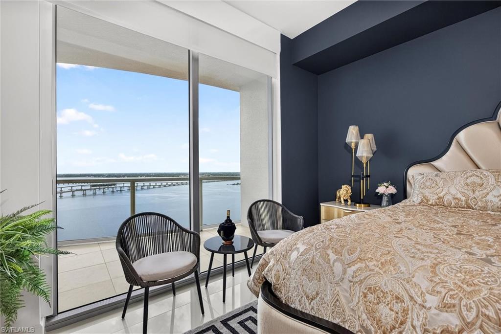 Floor-to-ceiling glass doors opening to a private balcony with water and bridge scenery