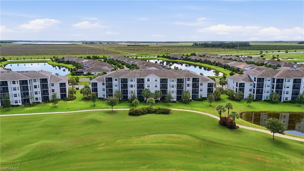 Multi-story residential buildings with private balconies, surrounded by expansive green spaces, mature landscaping, and reflective water features