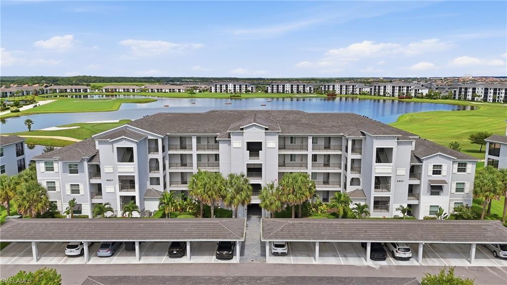Multi-story building with covered parking, balconies, and a golf course with water features in the background