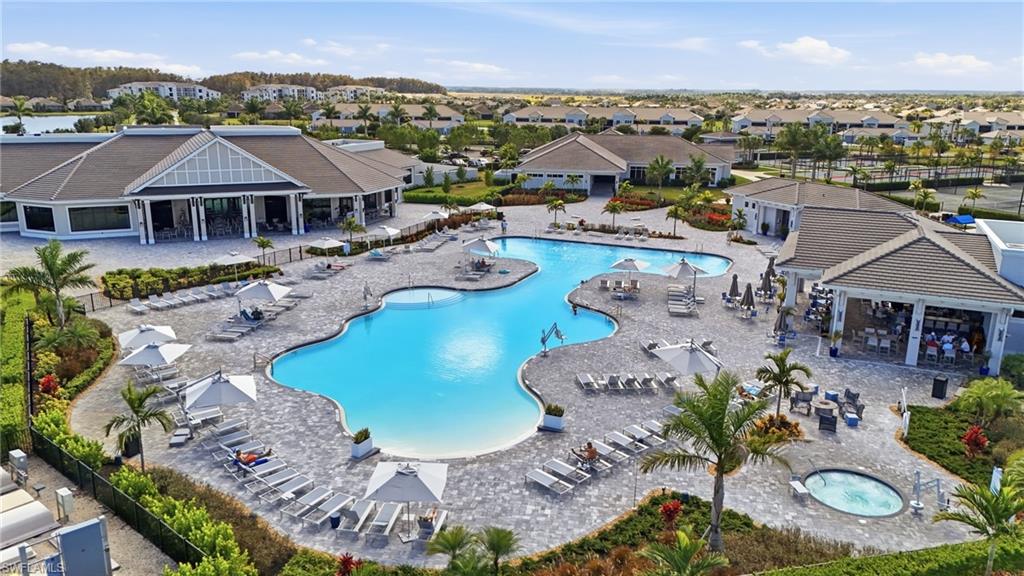 Expansive resort-style swimming pool, integrated spa, surrounding paver decking, and a contemporary clubhouse