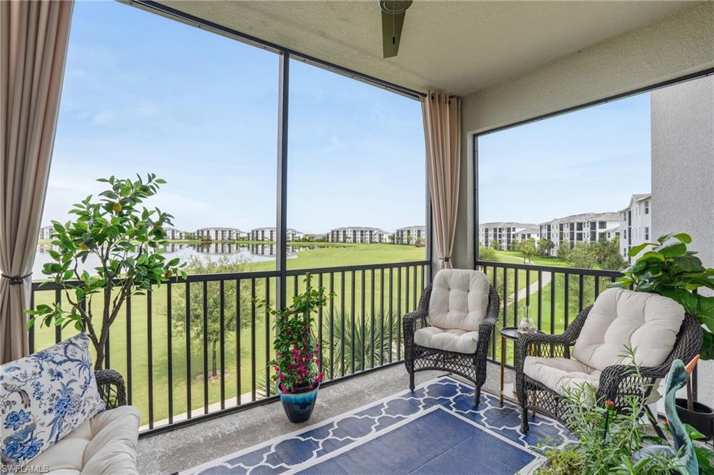 Screened-in balcony with a ceiling fan, overlooking a lake and green space