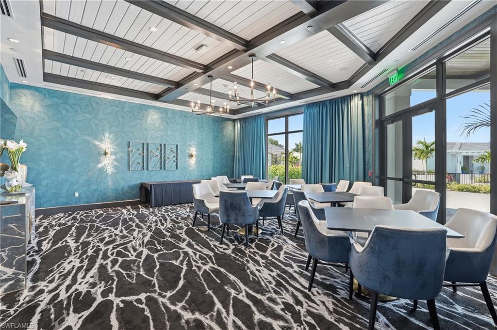 Textured accent wall, wood beam ceiling detail, expansive windows, multiple light fixtures, and patterned carpeting