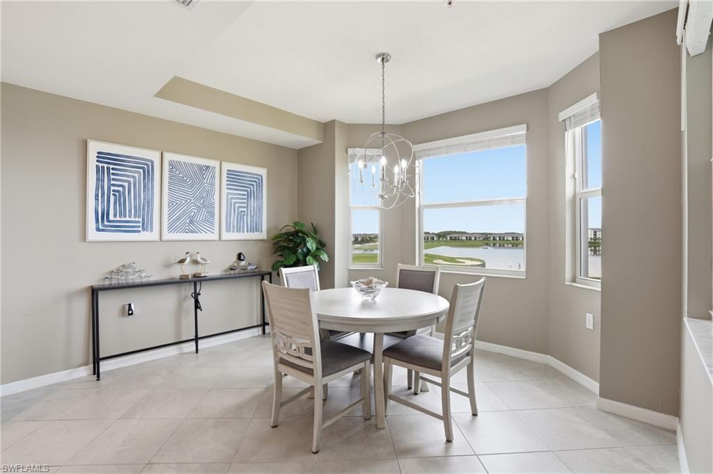 Recessed ceiling detail, contemporary chandelier, multiple windows, tile flooring, and neutral wall tones