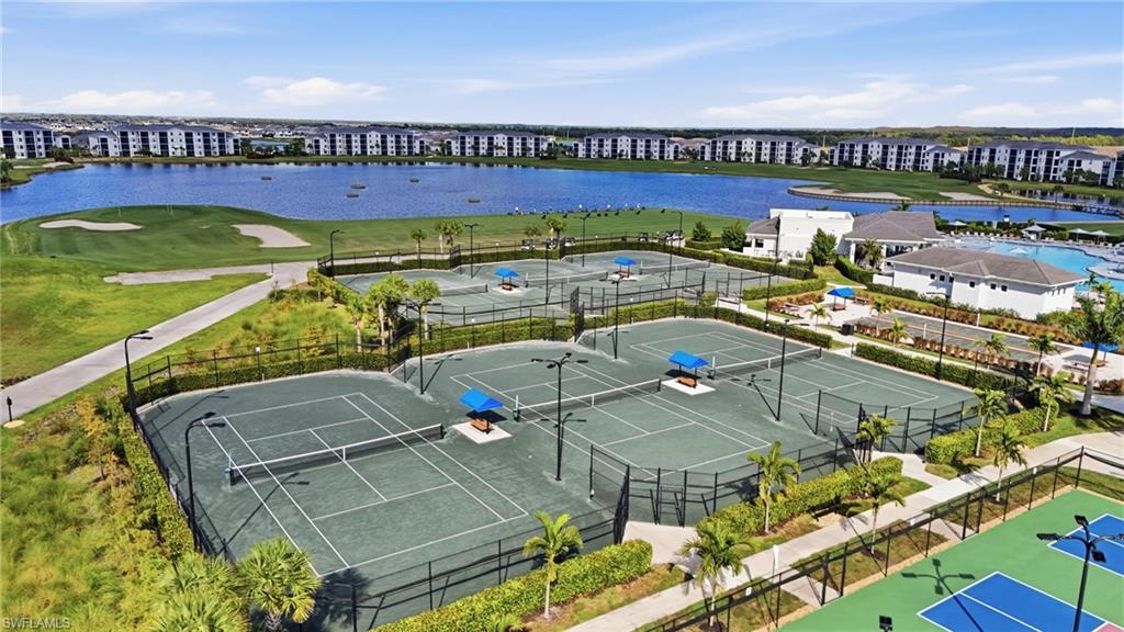 Multiple tennis courts with dark green surfaces, surrounded by fencing and landscaping