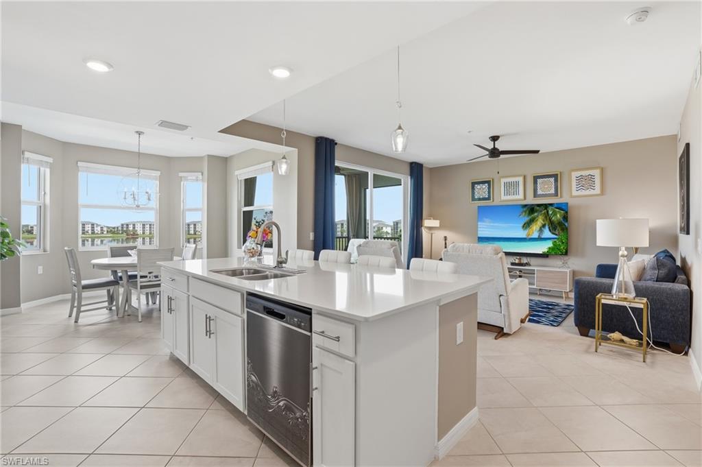 Open-concept living area with tile flooring, a kitchen island with sink and stainless steel dishwasher, and recessed lighting