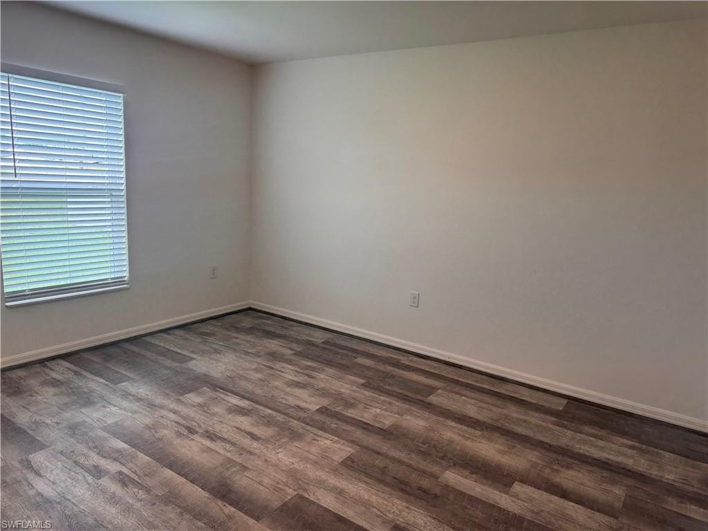 Unfurnished room featuring dark wood finished floors and baseboards