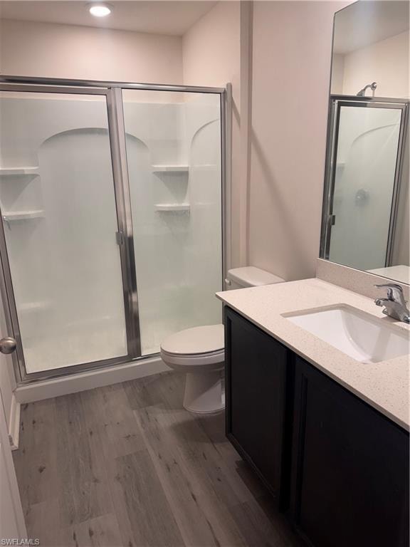 Bathroom with dark wood finished floors, vanity, a shower stall, and recessed lighting