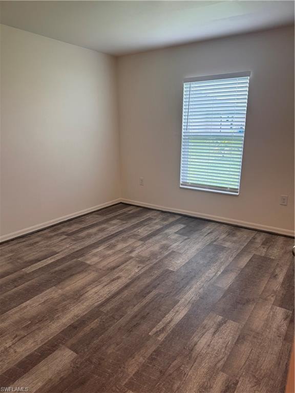 Spare room with dark wood-style floors and baseboards
