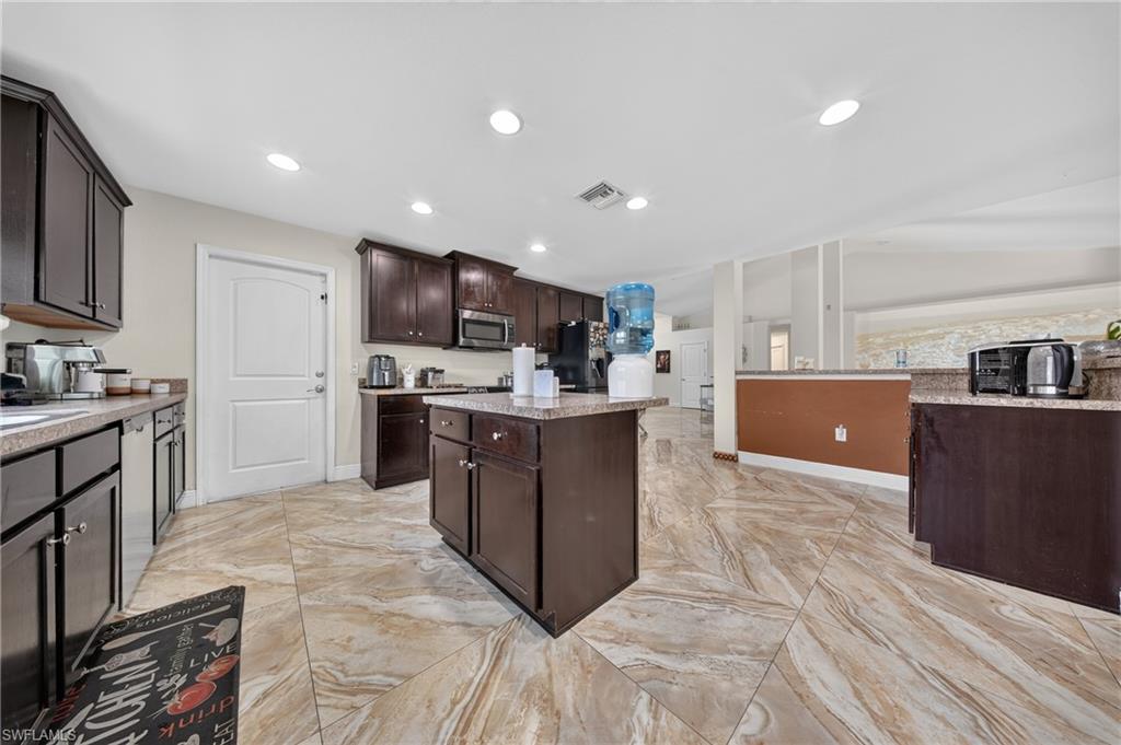 Kitchen featuring dark wood-finish cabinetry, a central island, light-toned countertops, tile flooring, and recessed lighting