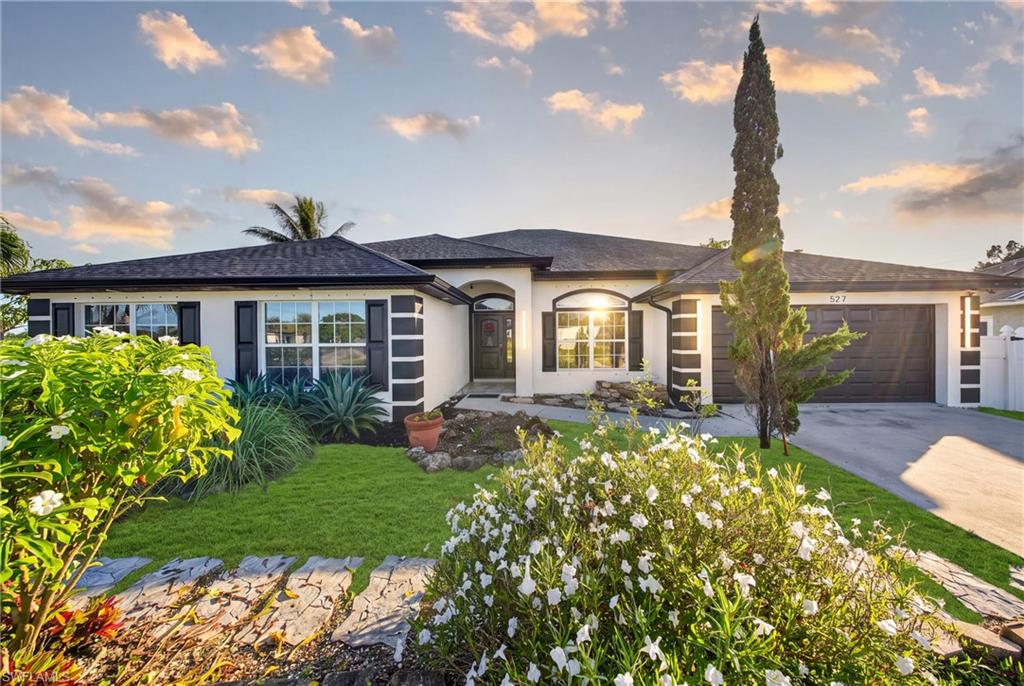 Single-story residence featuring a dark shingle roof, decorative window shutters, an arched entryway, and a two-car garage