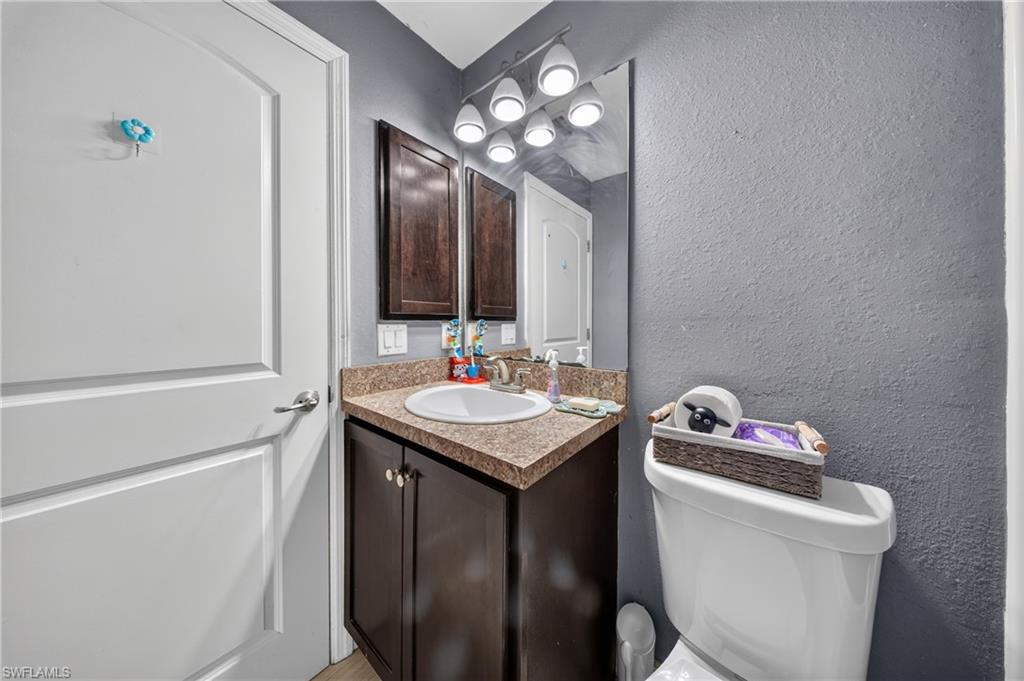 Elegant bathroom featuring a dark wood vanity with granite countertop, round undermount sink, and bronze-framed mirror