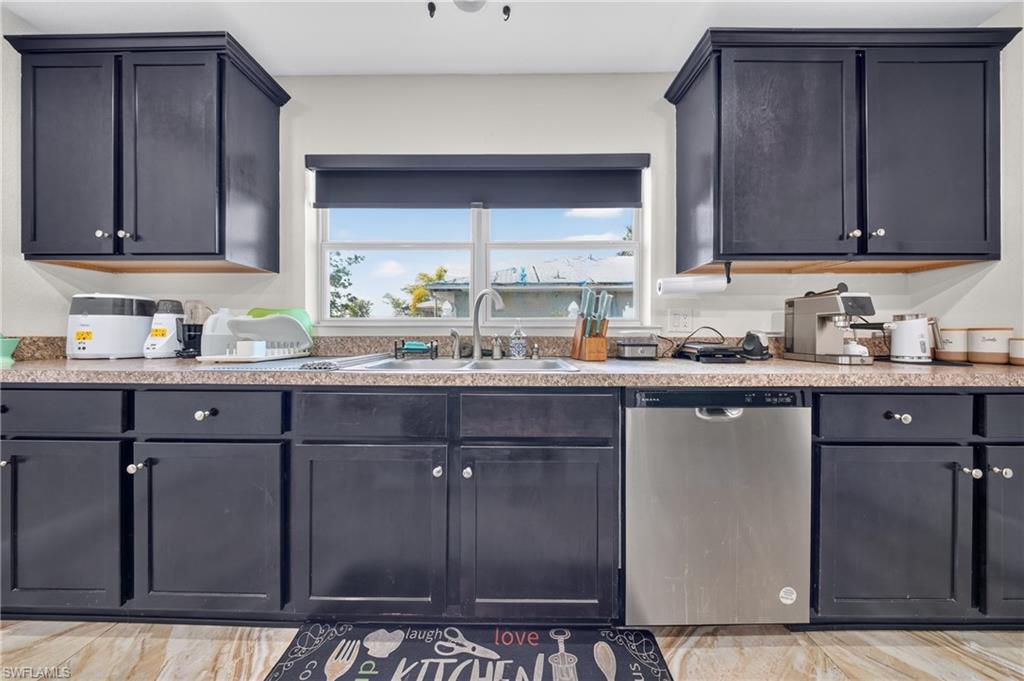 Kitchen featuring dark-finish cabinetry, light-toned countertops, a stainless steel dishwasher, and wood-finish flooring