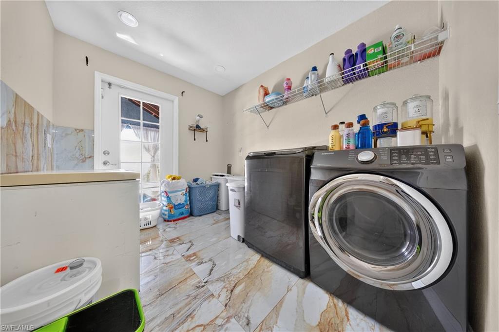 Laundry area featuring a full-light exterior door, marble-finish wall tile, and patterned floor tile