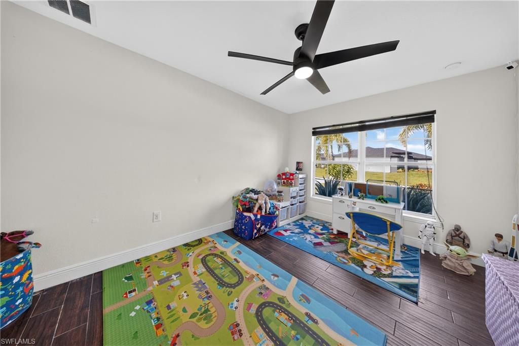 Bright room with wood-finish flooring, a large window, a ceiling fan, and white walls
