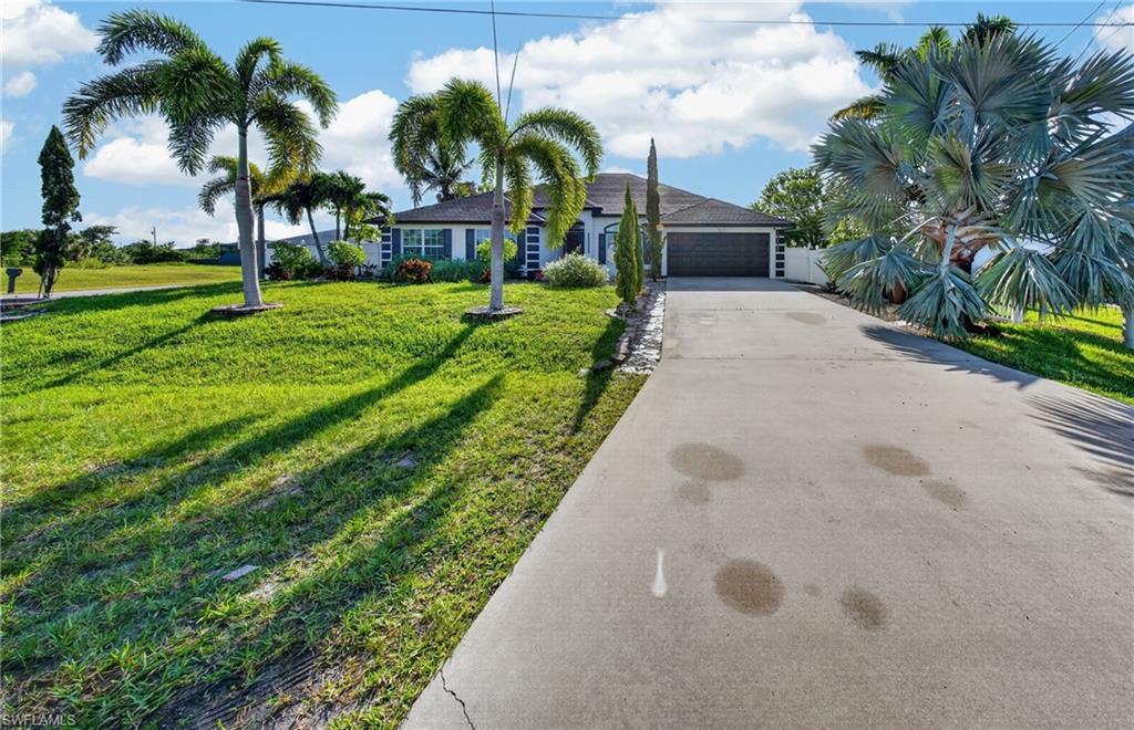 Single-story residence featuring a two-car garage, concrete driveway, and a white privacy fence